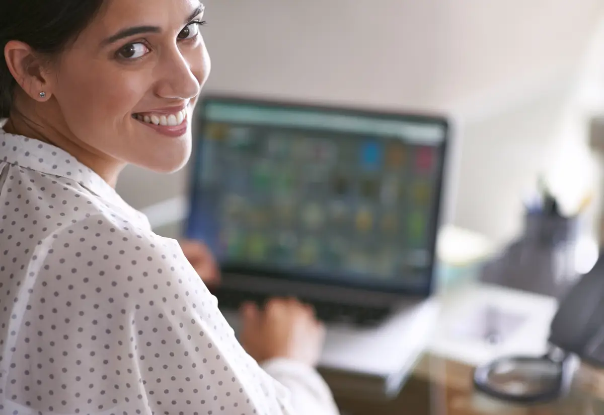 Working with a smile A young woman happily working at her computer