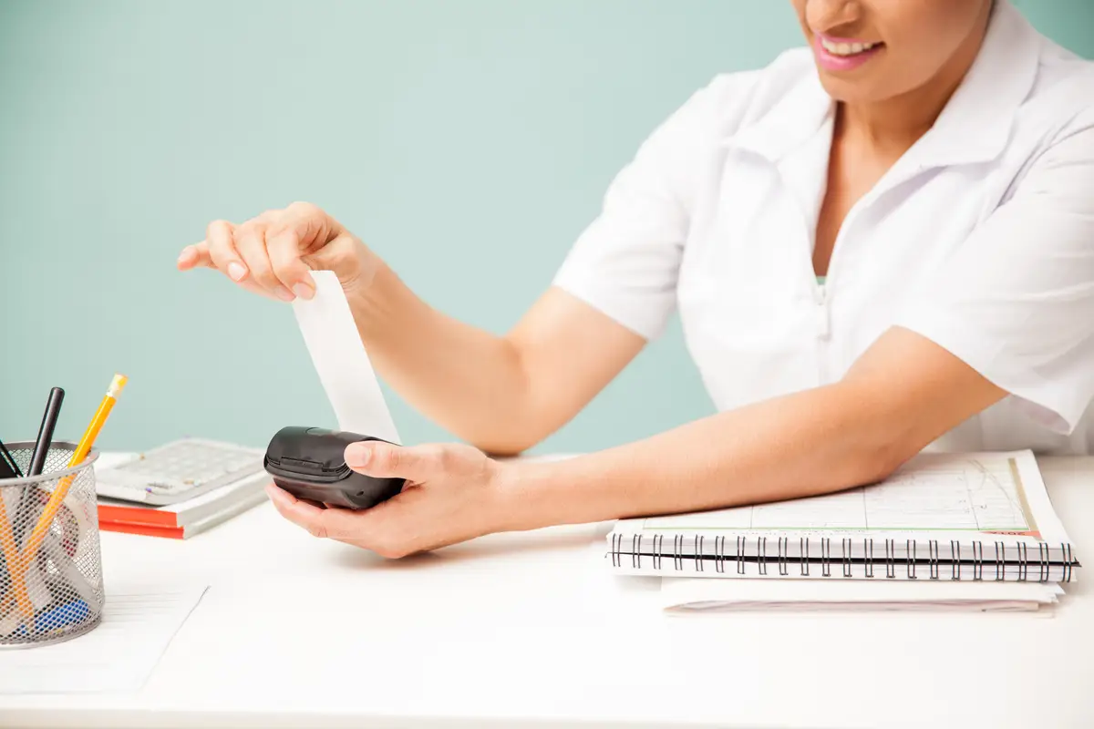 Female masseuse printing a payment receipt and smiling at a beauty spa. Closeup with some copy space