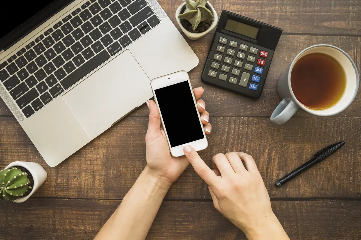 Hands using smartphone at workspace
