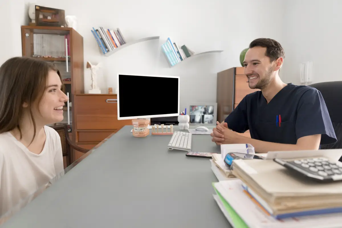 Happy patient consulting to male dentist at dental clinic