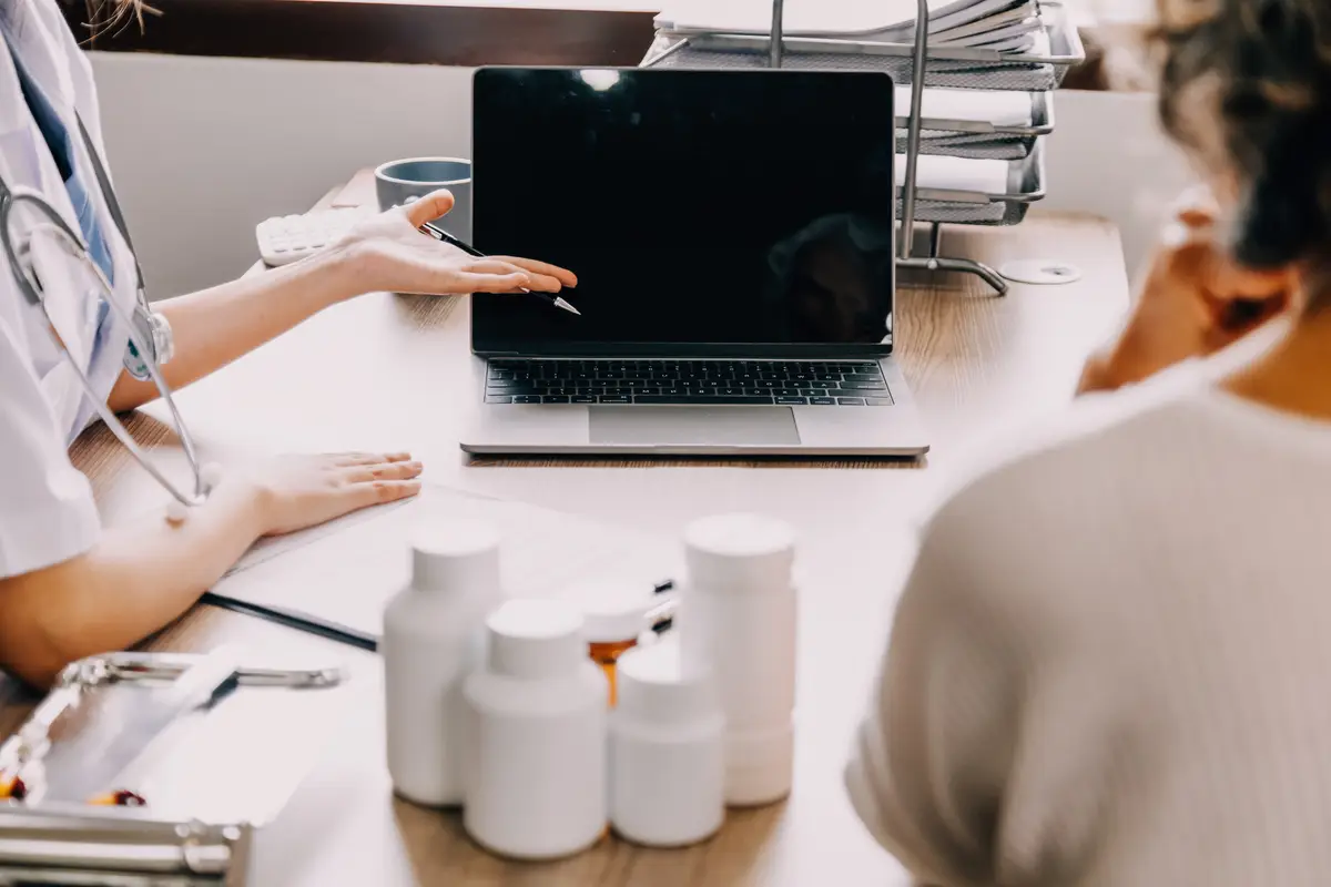 Smiling female doctor talking with senior patient in clinic office