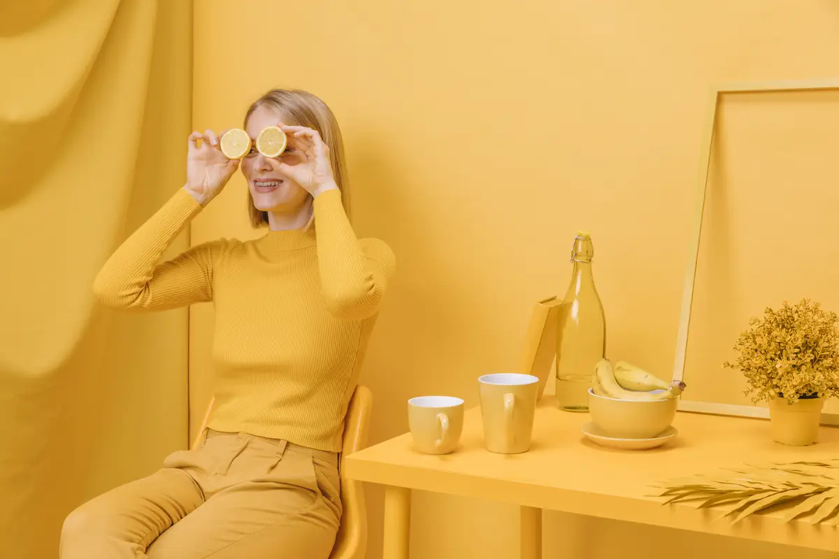 Woman holding lemons in front of eyes in a yellow scene
