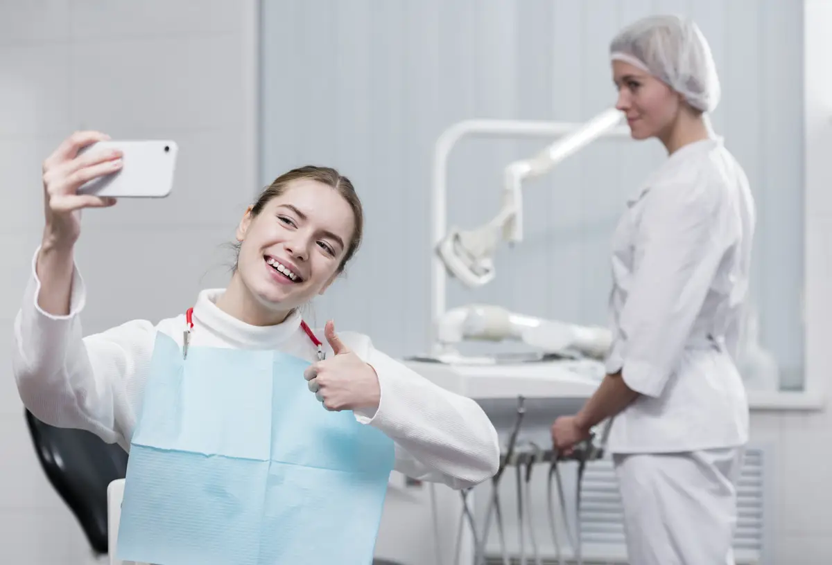 Happy young woman taking a selfie at the dentist