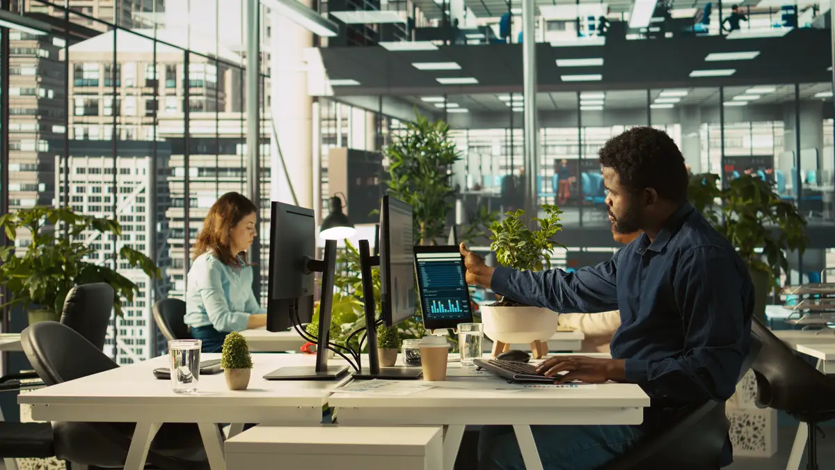 Employee in office leaving desk to present revenue figures on tablet