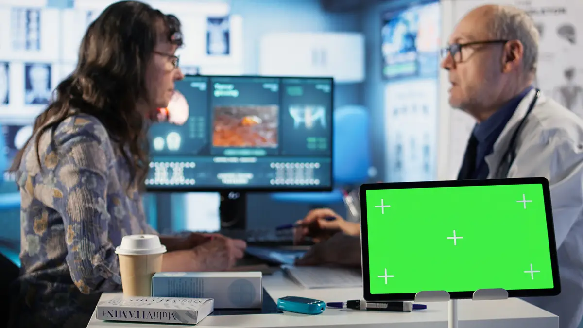 Old patient and specialist at check up visit next to chroma key display