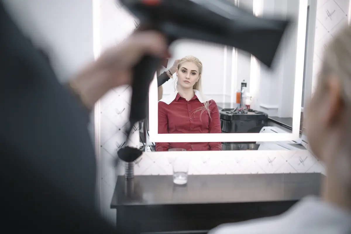 Hairdresser styling hair of young woman