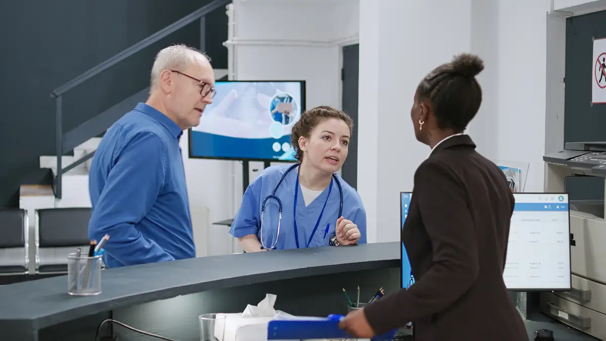 Senior man making credit card payment at hospital reception counter, paying for medical consultation and prescription treatment in health center lobby. Electronic insurance purchase.