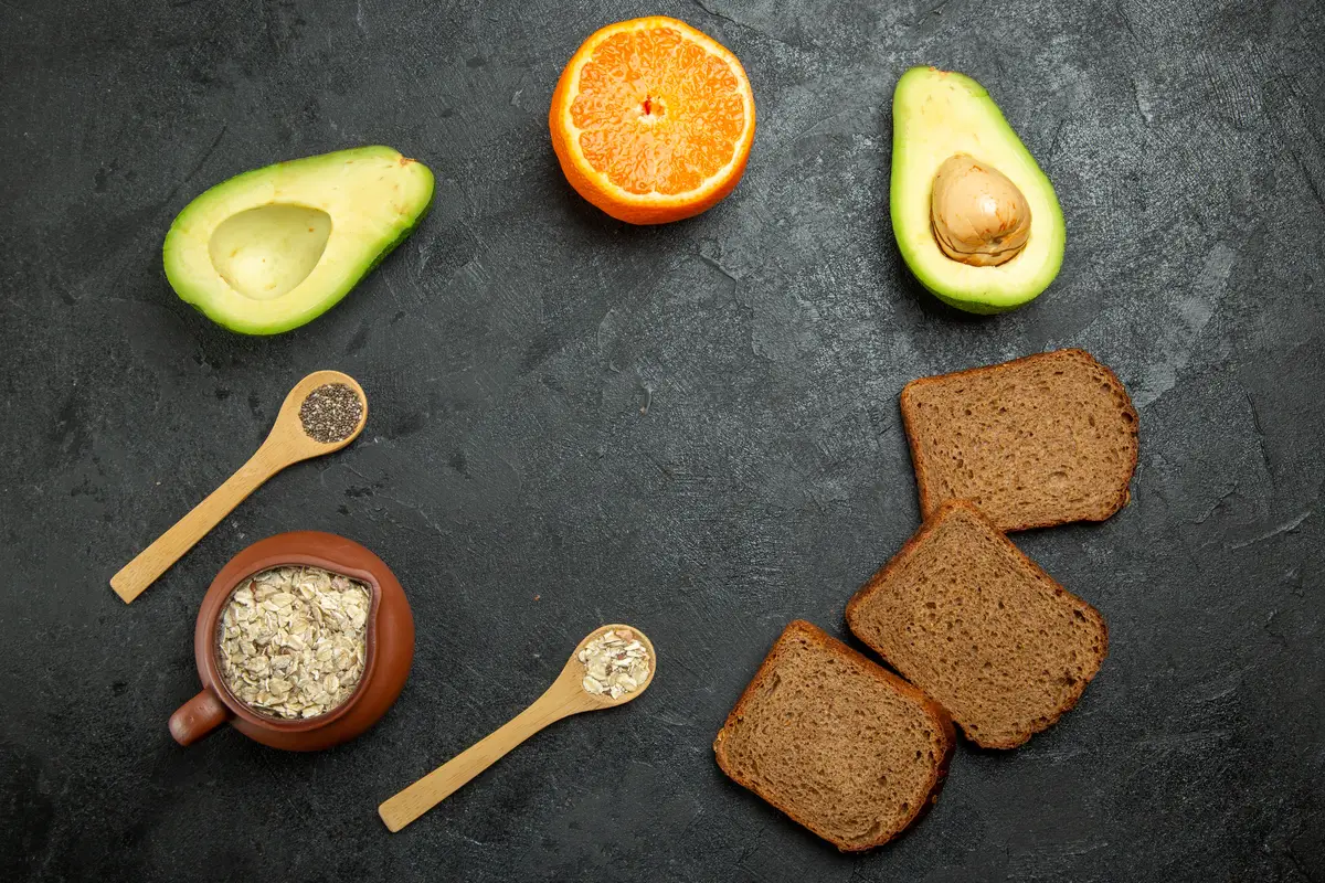 Top view of dark bread loafs with avocados on grey surface