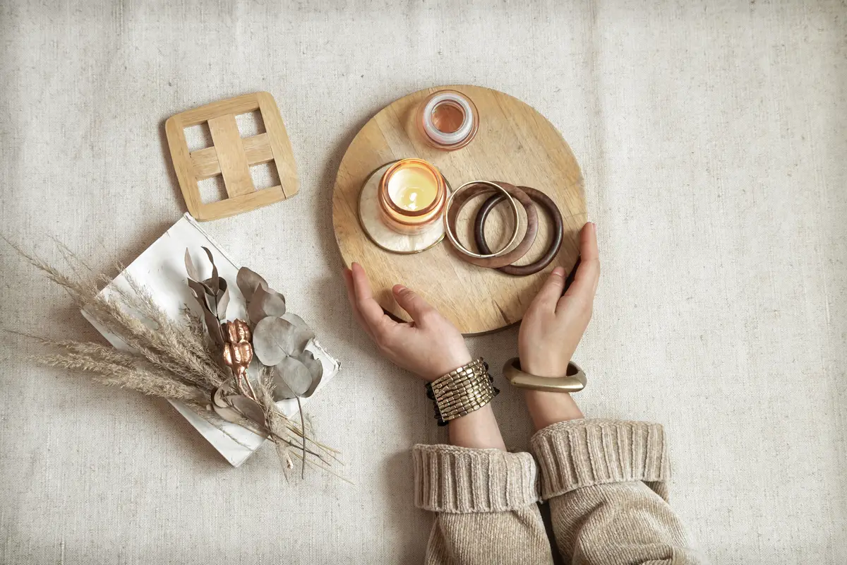 Still life with female hands in bracelets on the space of wooden decor and dried flowers top view.