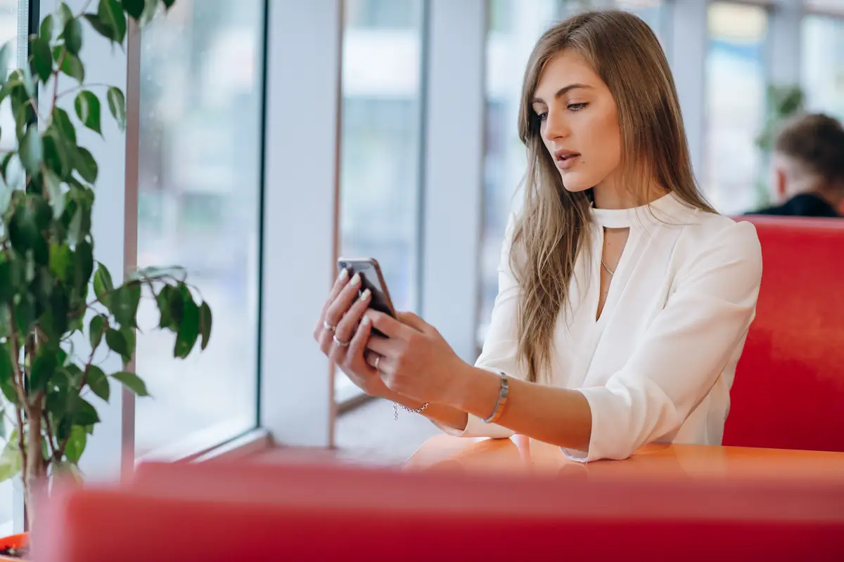 Woman looking at her phone sitting in a coffee shop
