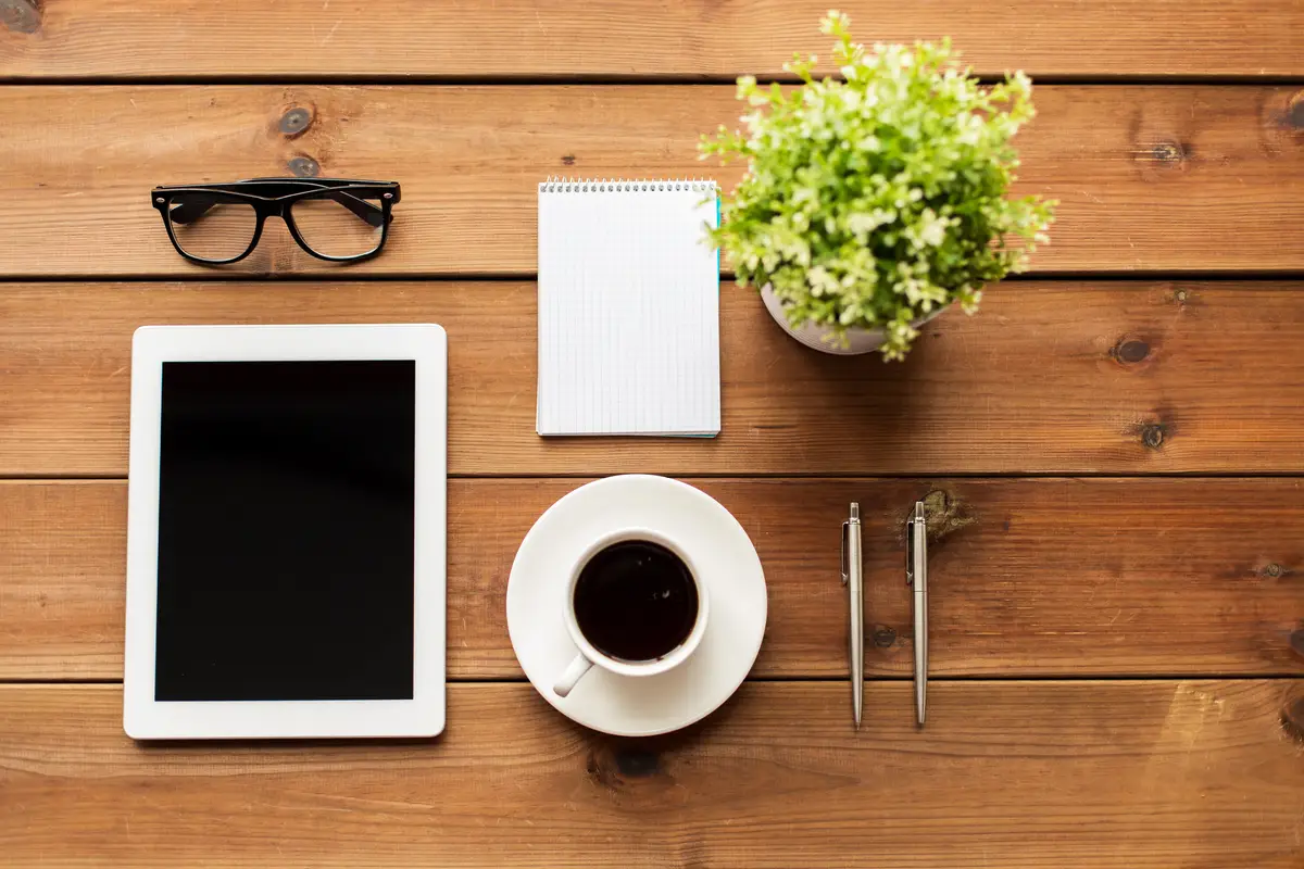 education, business and technology concept -close up of tablet pc computer, coffee cup, eyeglasses and notepad on wooden table