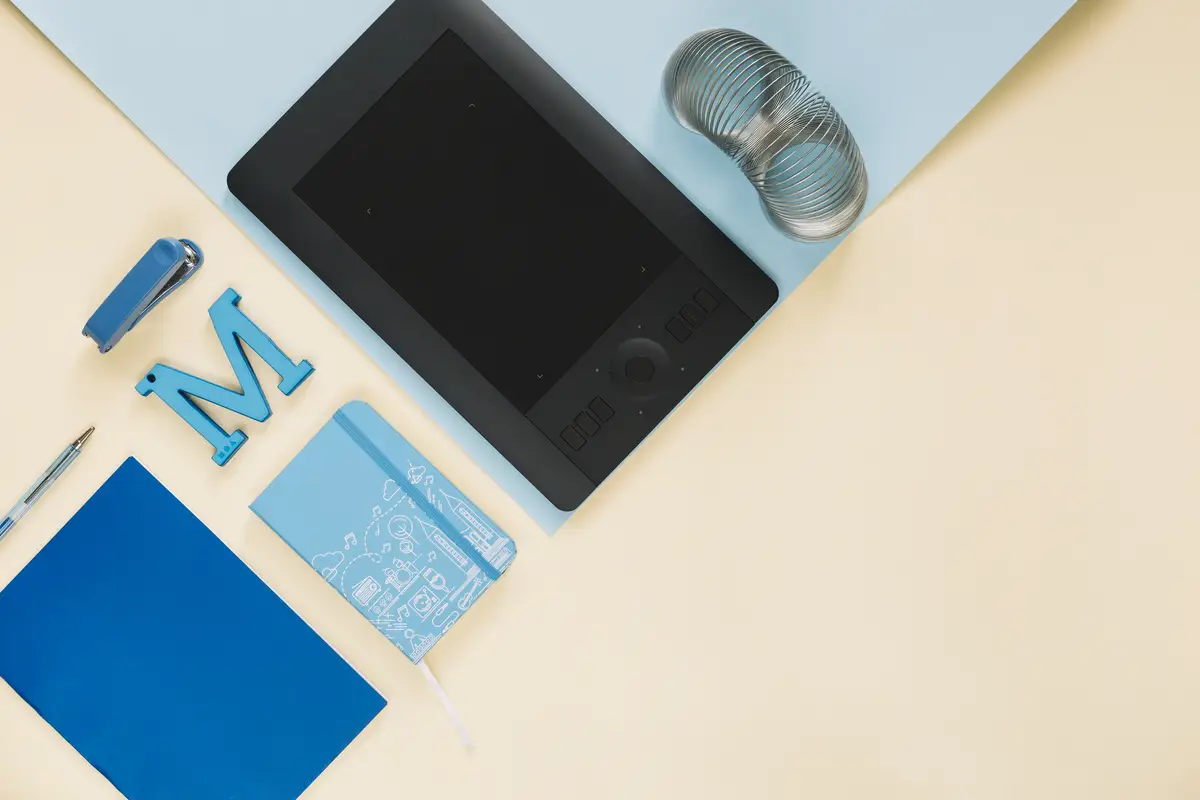 Overhead view of graphic digital tablet and stationeries on paper backdrop