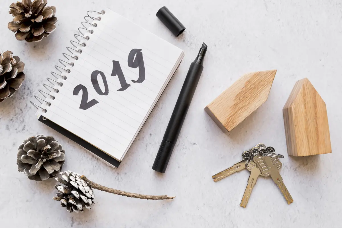 Pinecones; keys; wooden house blocks and 2019 written on notepad with felt tip pen on white textured surface