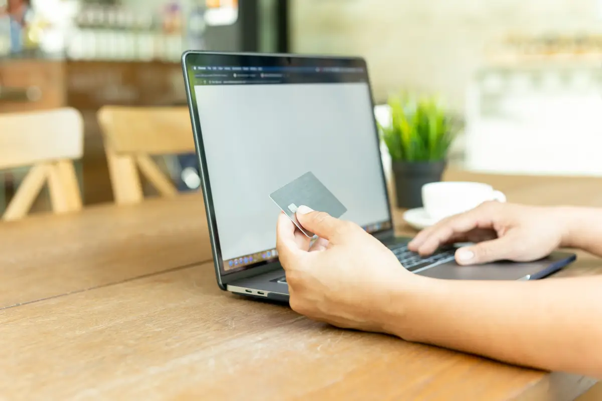 Businessman online working hand holding credit card and using laptop in cafe.