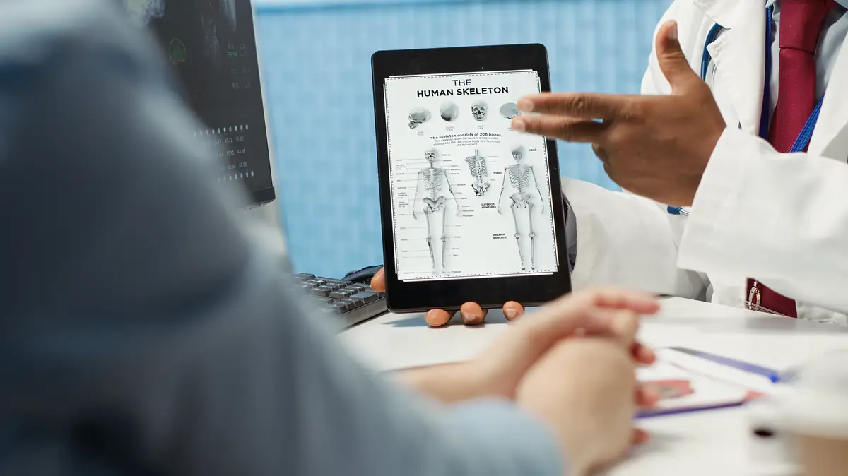 General practitioner pointing at illustration to explain diagnosis to woman