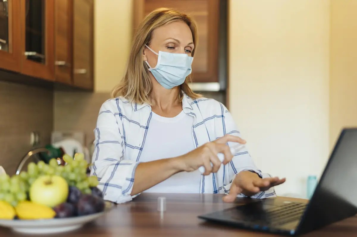 Woman at home during quarantine with medical mask and laptop