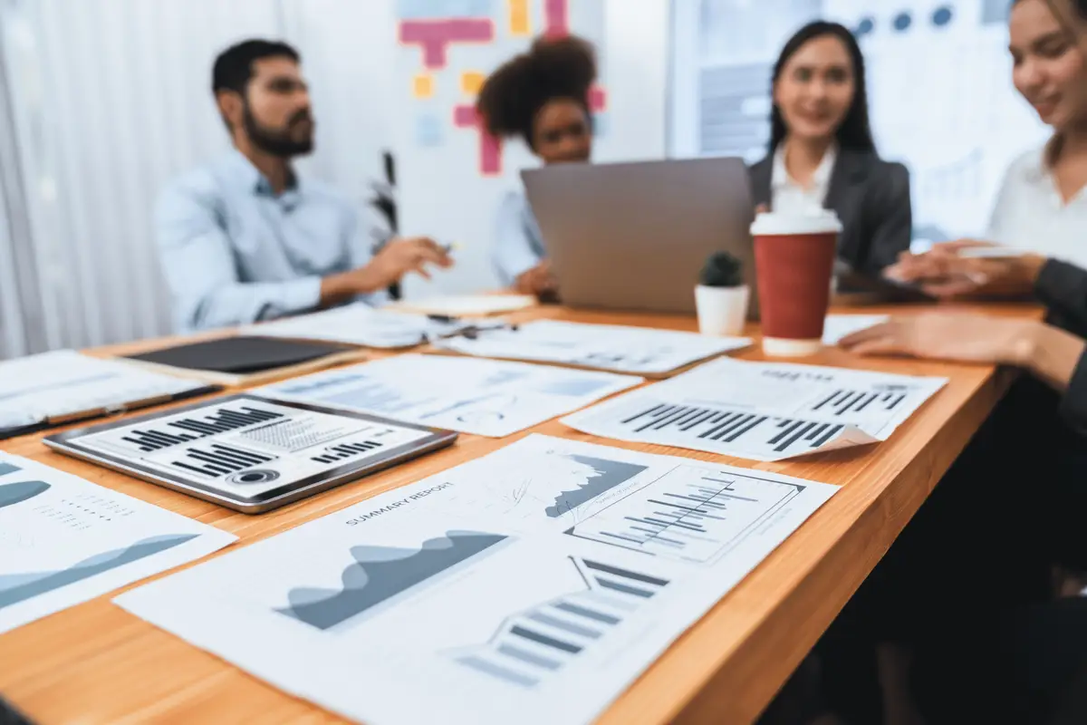 Focus financial dashboard paper showing graphs and chart with blurred background of diverse business people analyzing business data by BI Fintech technology for business marketing indication Concord