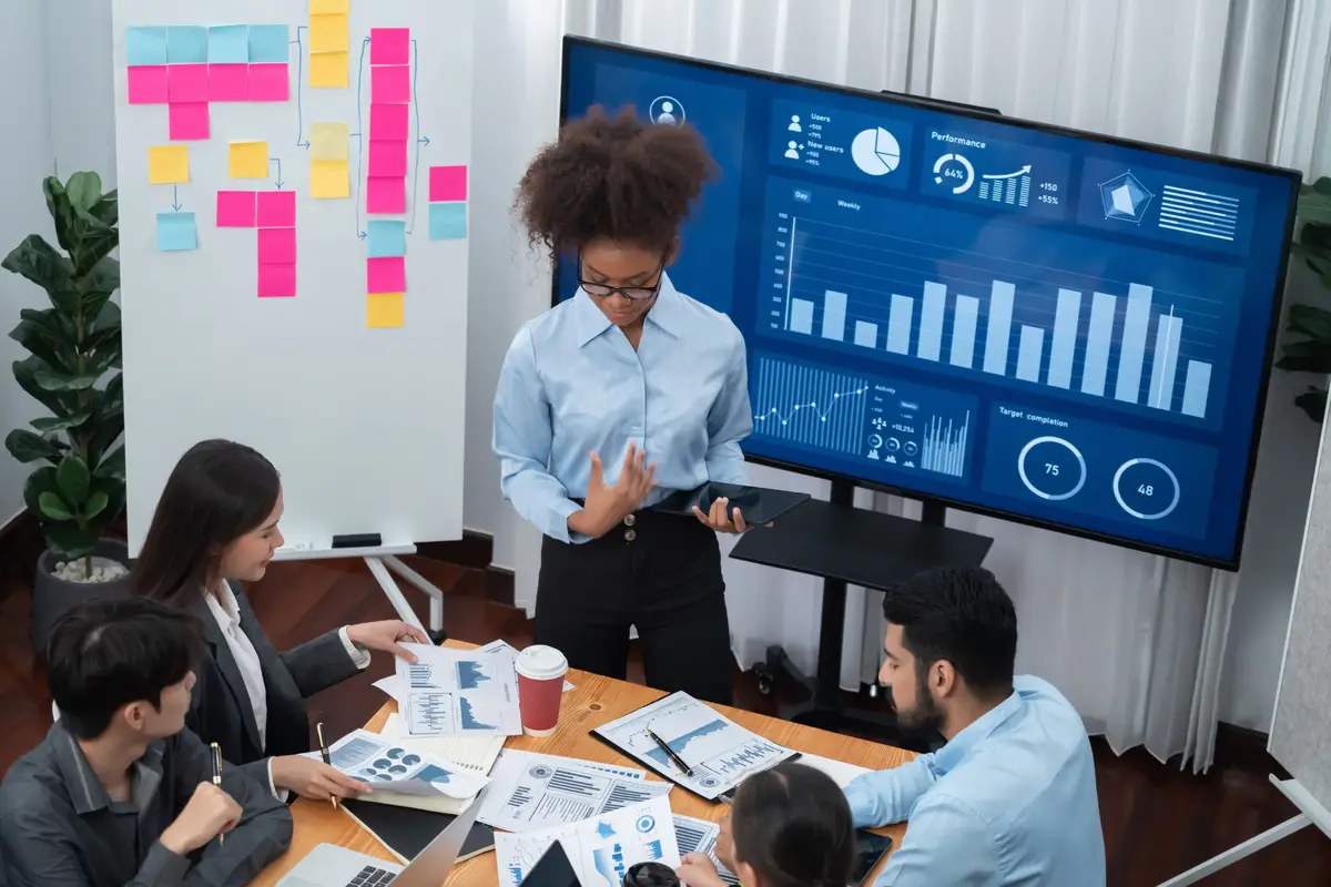 Young african businesswoman presenting data analysis dashboard on TV screen in modern meeting Business presentation with group of business people in conference room Concord