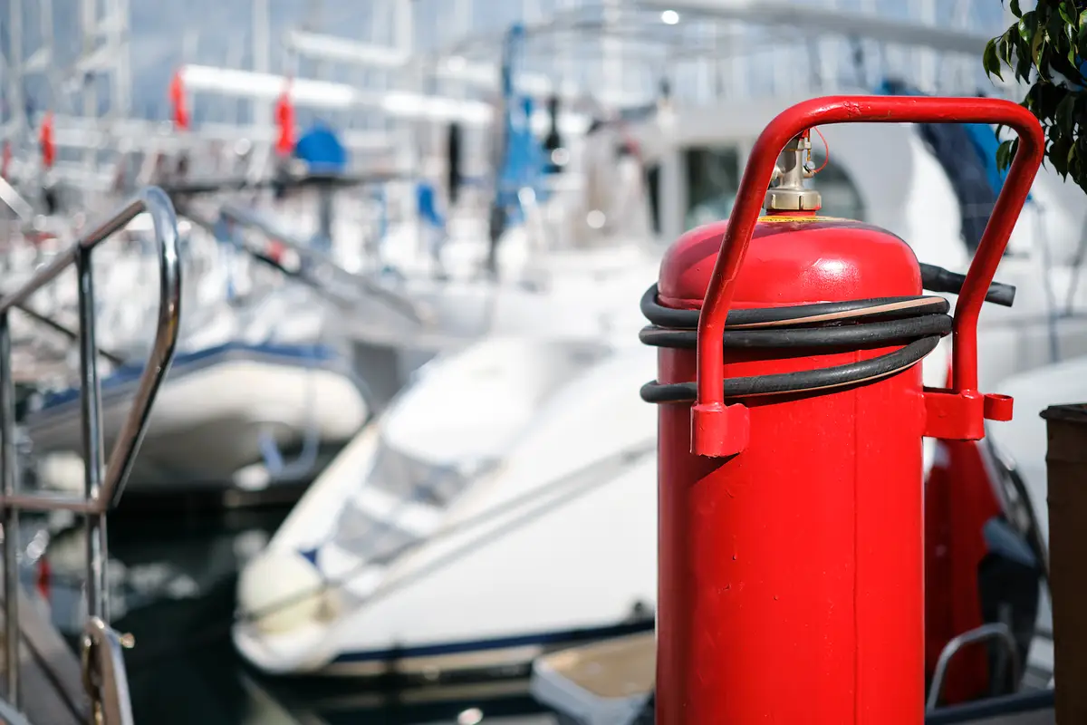 Fire extinguisher closeup on the mooring of the yacht club blurred background providing fire protection and safety prevention