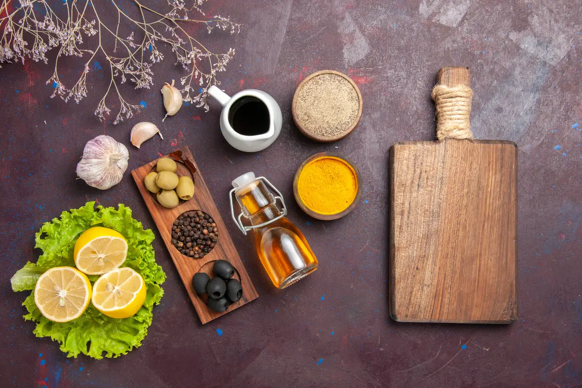 Top view of fresh lemon slices with green salad and olives on dark