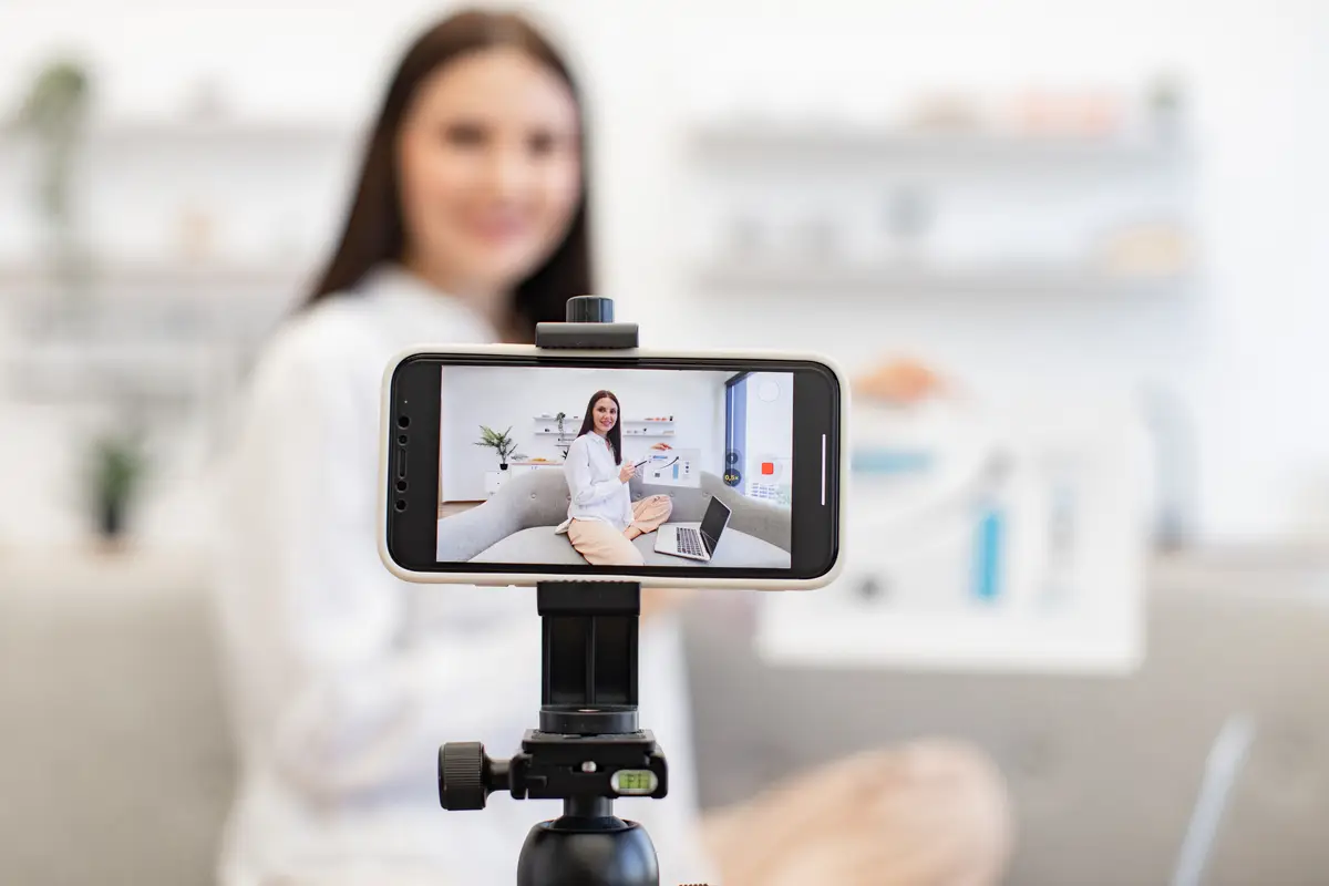 Young caucasian brunette financier woman filming herself on cell phone