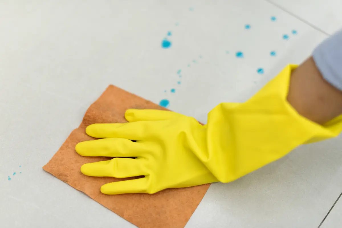 Woman wearing yellow rubber gloves and cleaning the surface