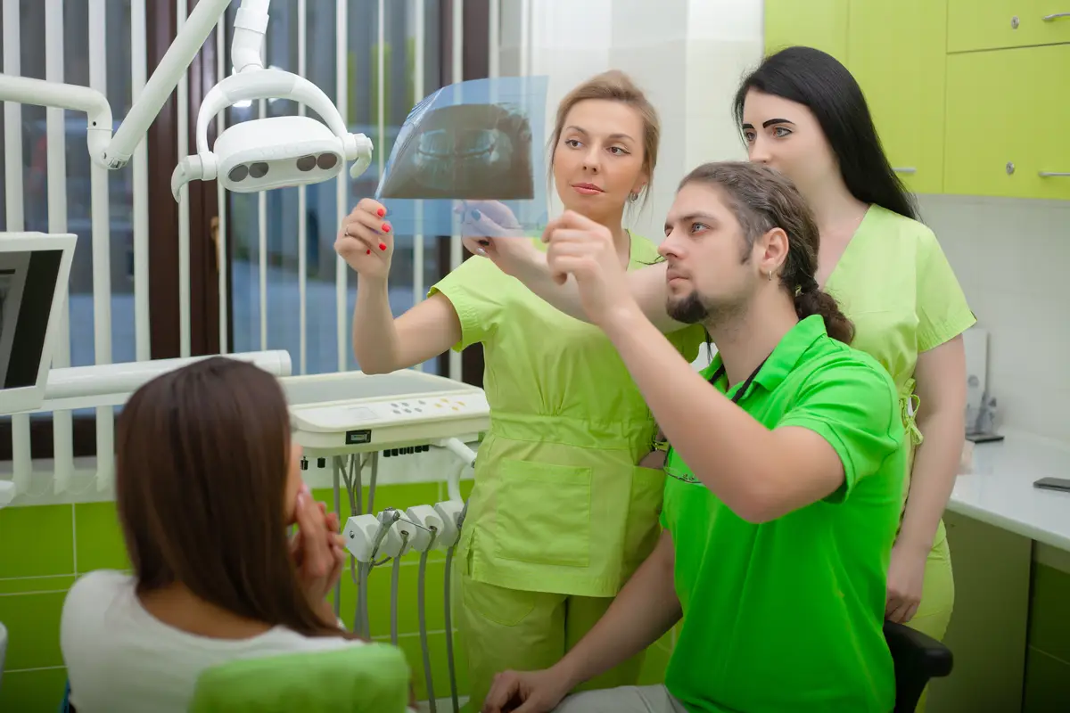 Woman sitting in dental chair at medical center while professional doctor fixing her teeth