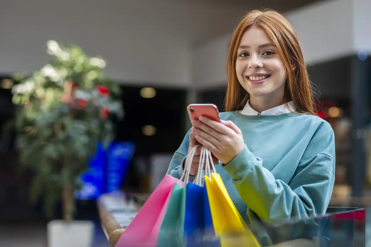 Smiling woman holding phone and looking at photographer