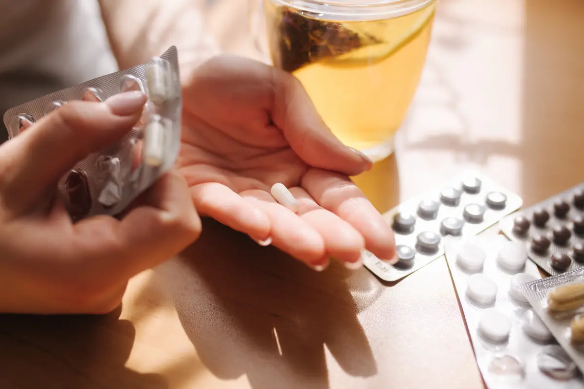 Terapia intravenosa versus oral na bacteremia por Staphylococcus aureus 4 Close up of woman's hands hold pills Hand with pills and black tea with lemon Immunity Vitamines