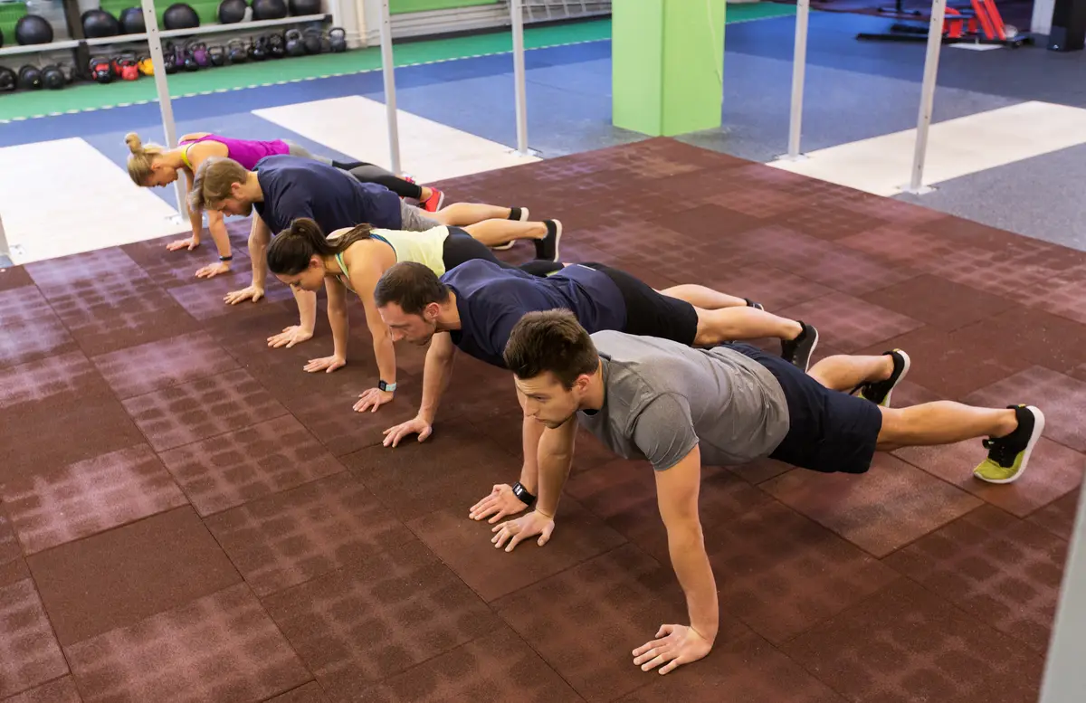 fitness, sport, exercising, training and healthy lifestyle concept - group of people doing straight arm plank in gym