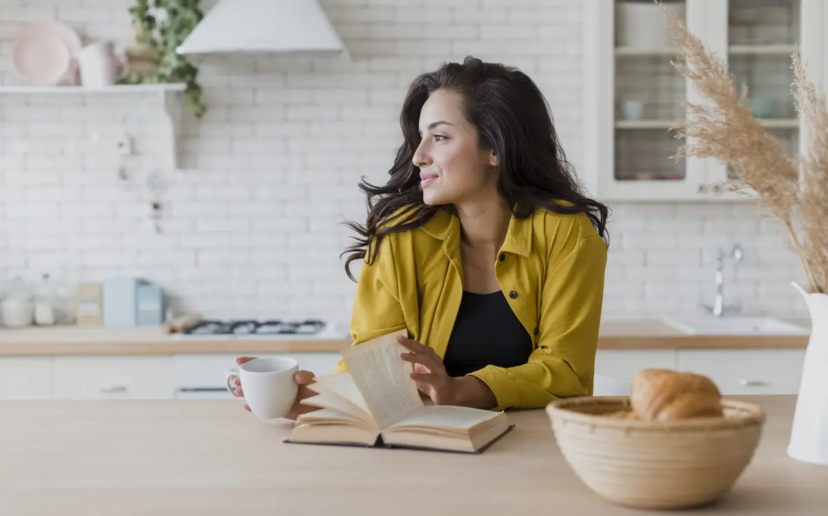 Medium shot woman with book and cup of coffee