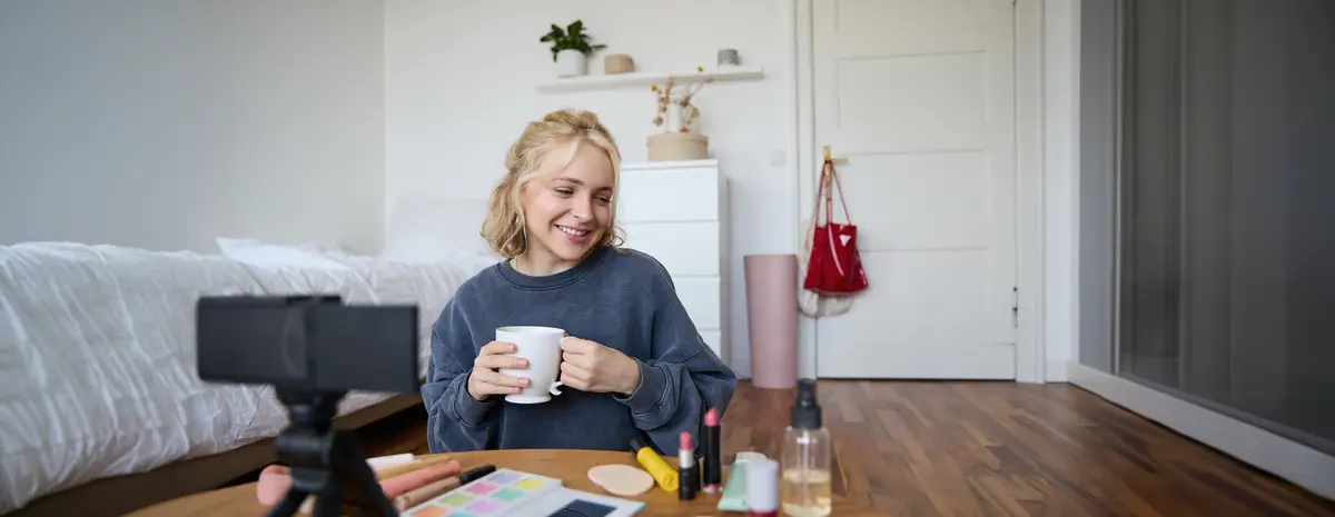 Portrait of cute blond woman video content maker vlogger recording on digital camera in bedroom