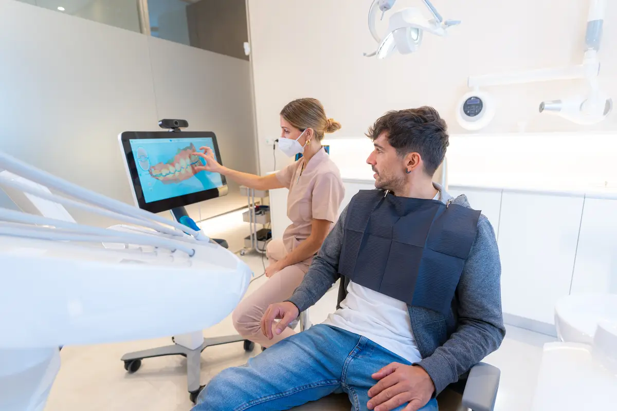 Dentist using modern technology to explain the dental procedure to a man sitting on the clinic