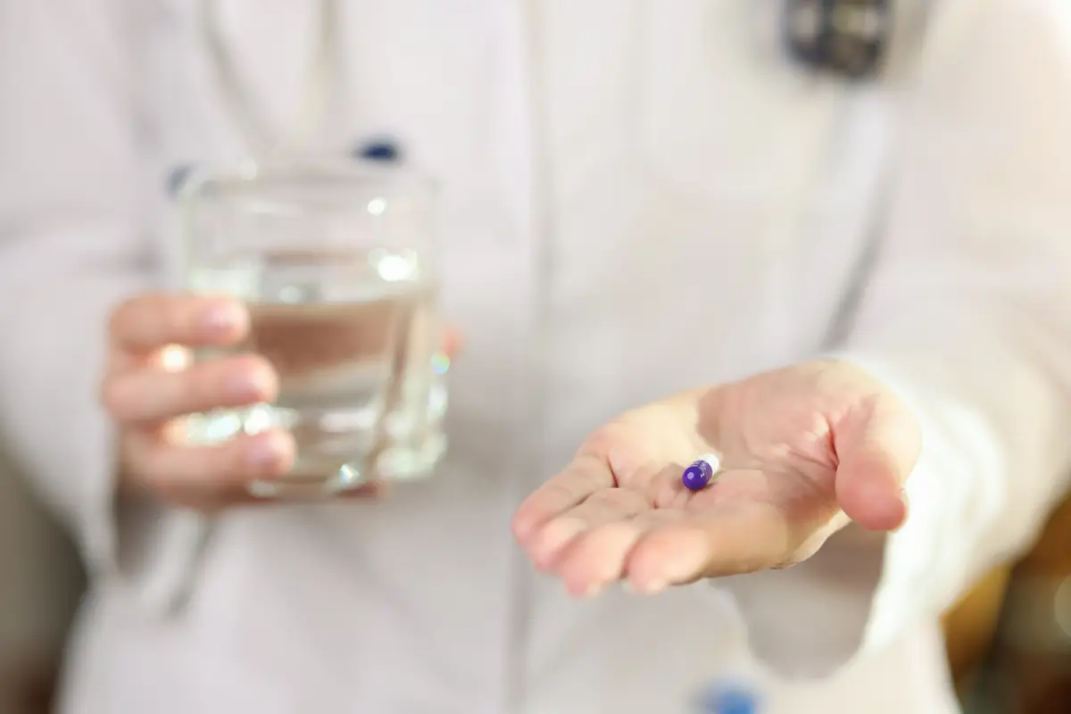 Professional doctor holds glass of water and pill in hands