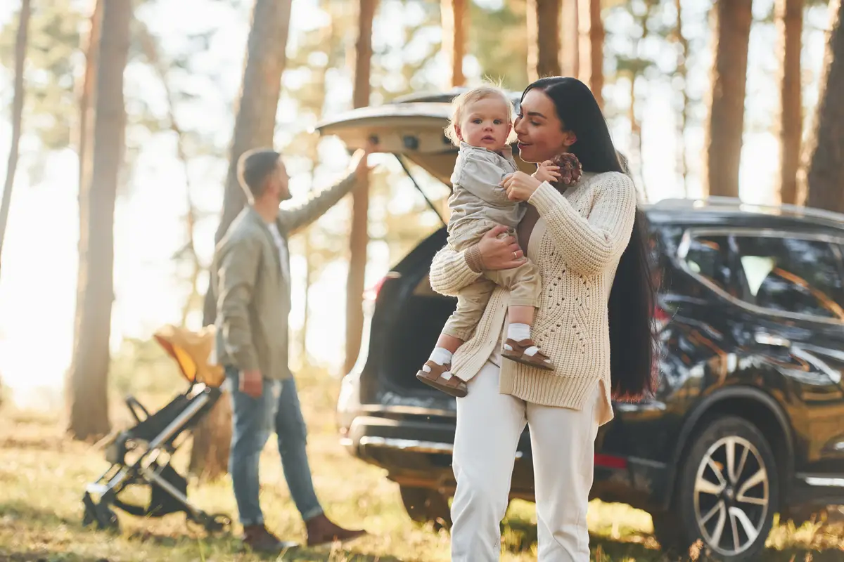 Woman holding girl Happy family of father mother and little daughter is in the forest