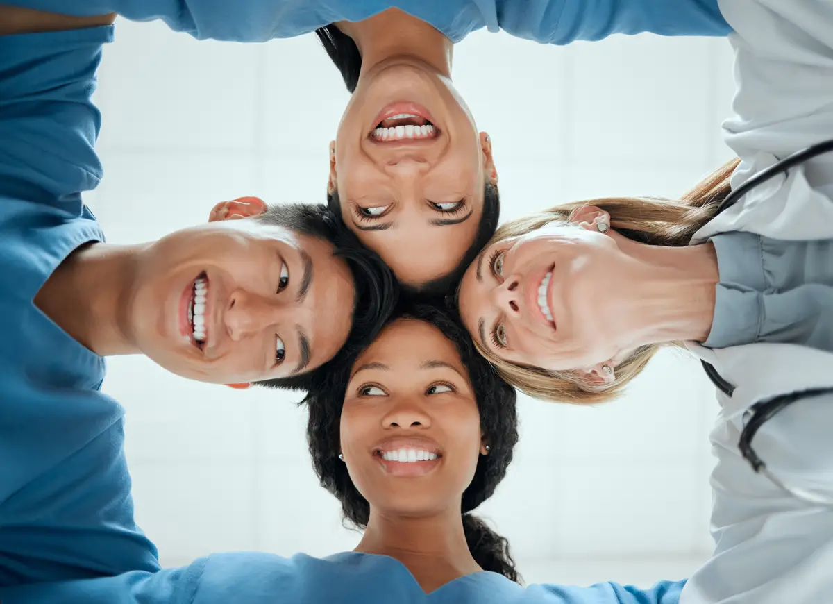 Happy teamwork or faces of doctors in huddle with a smile collaboration for healthcare mission goals Smiling team building or low angle of nurses with group support motivation or private secrets