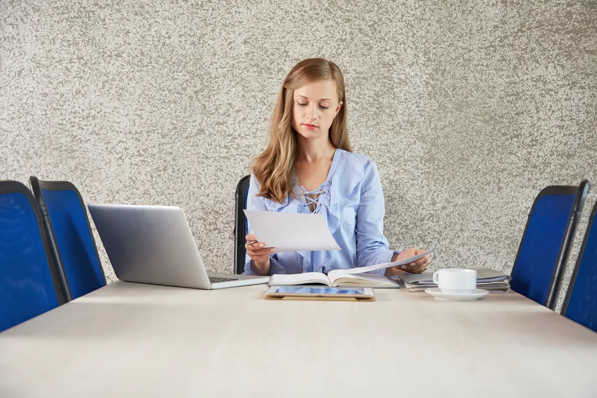 Como fechar empresa nos EUA sem multas: passo a passo 2 Waistup of young business lady sitting at desk in the office looking at the document