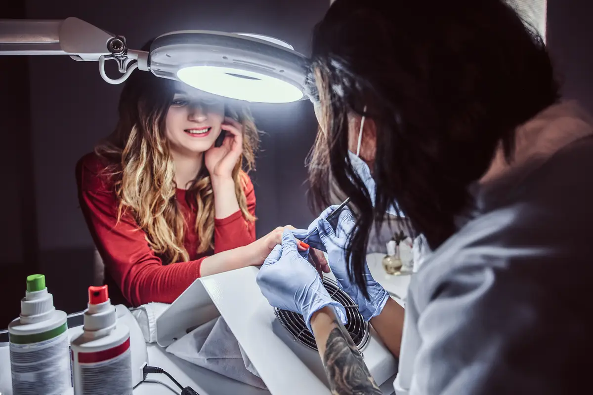 Manicure procedure in a beauty salon - Beautician making long transparent artificial nails to a female client