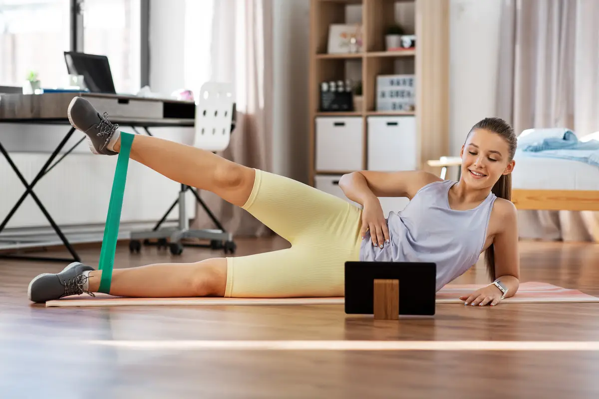 teenage girl with tablet pc exercising at home