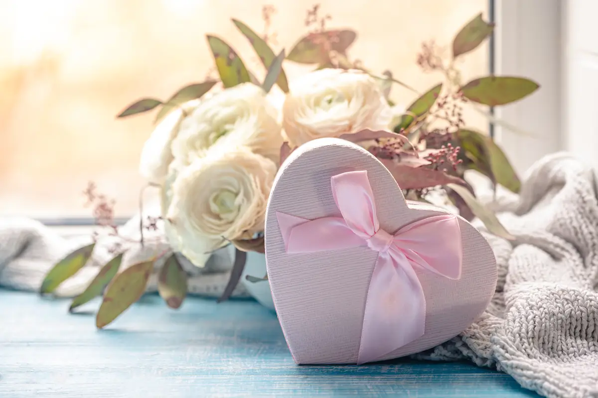 Composition with a pink heartshaped gift box and flowers