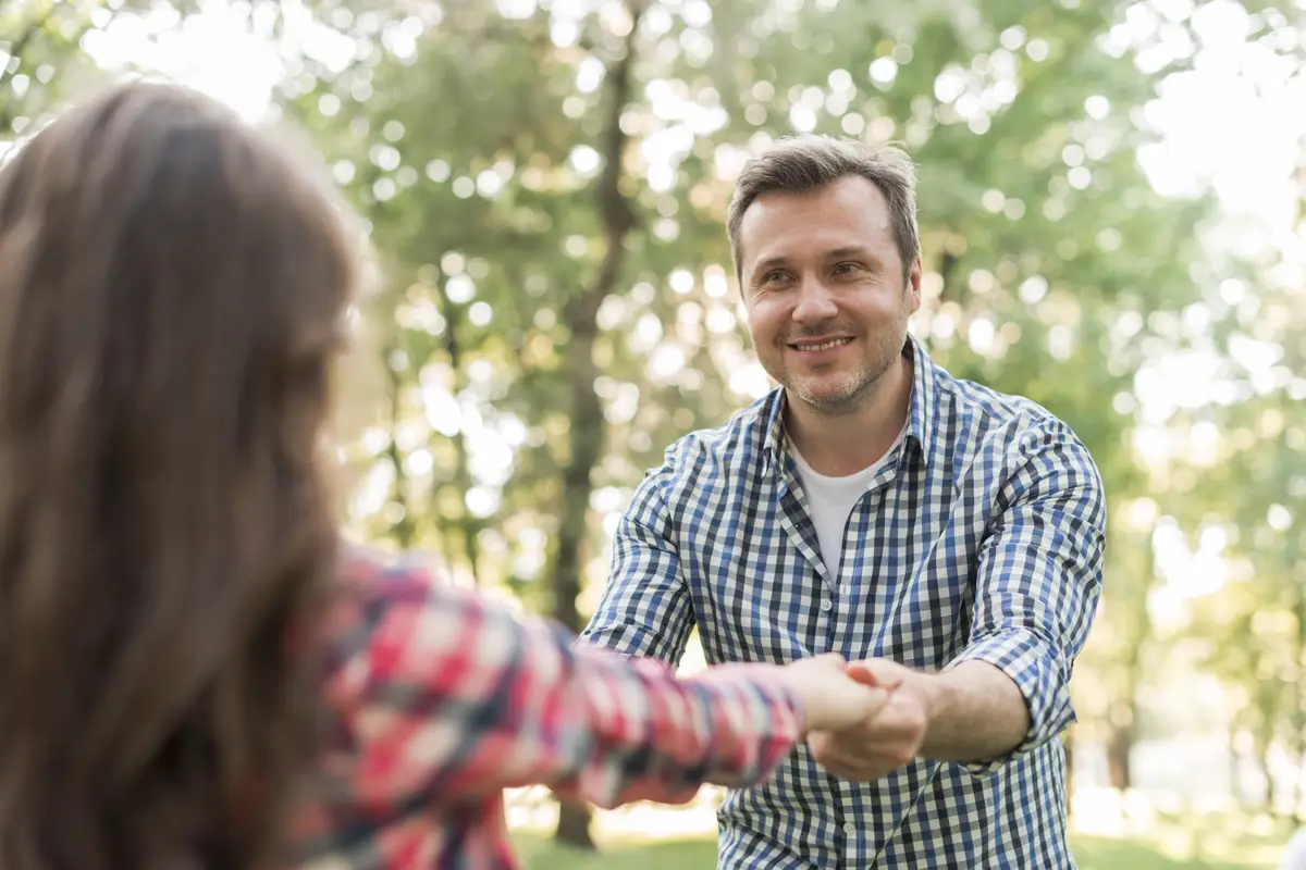 Happy man pulling his daughter and playing at park
