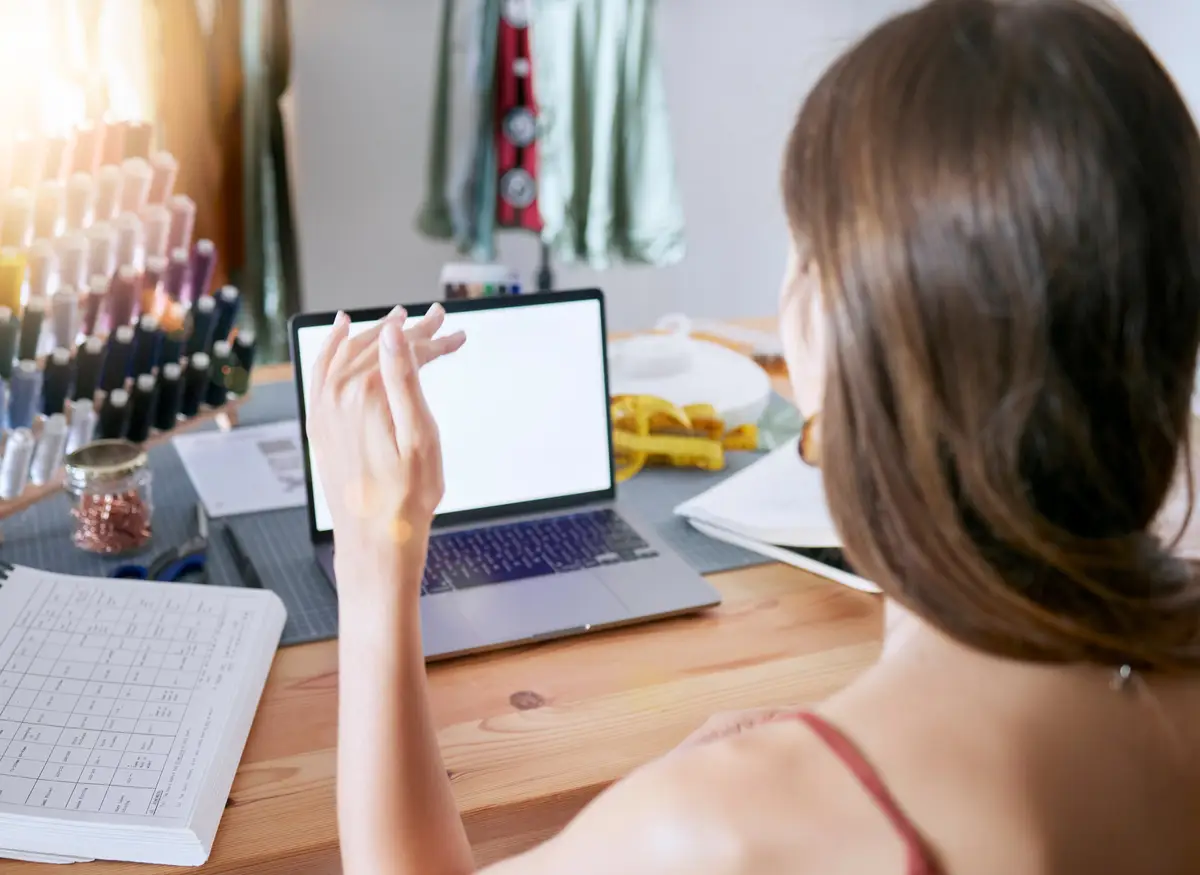 Laptop fashion and designer video call consulting with empty screen for expert communication Creative planning and virtual conversation with woman at design work desk in office with mock up