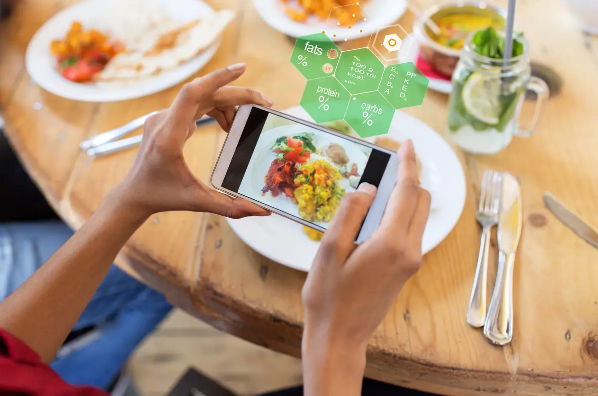 hands with smartphone and food at restaurant