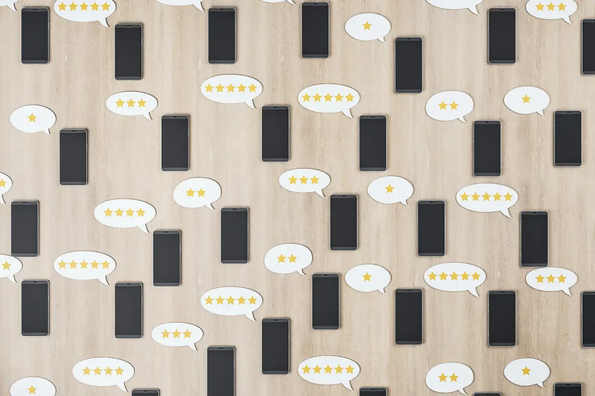 Social network rating concept with black cell phones on wooden surface and speech bubbles with stars