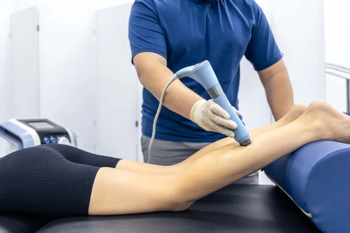 Physiotherapist treats patient leg with rehab device calf recovery session