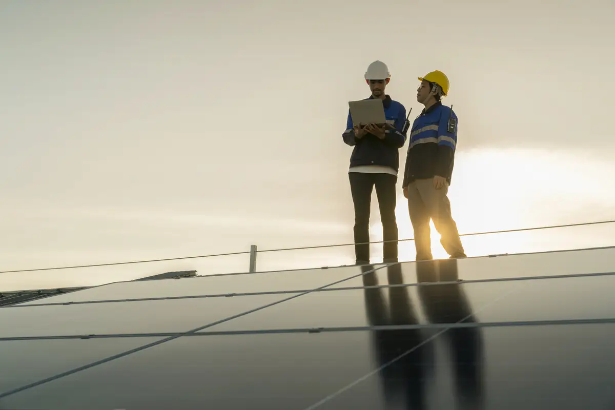 Specialist technician professional engineer with laptop and tablet maintenance checking installing solar roof panel on the factory rooftop under sunlight Engineers team survey check solar panel roof