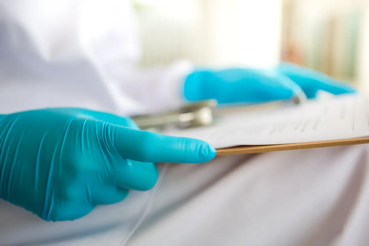 Quando evitar práticas não recomendadas em higiene das mãos 4 Hands with latex gloves holding a clipboard