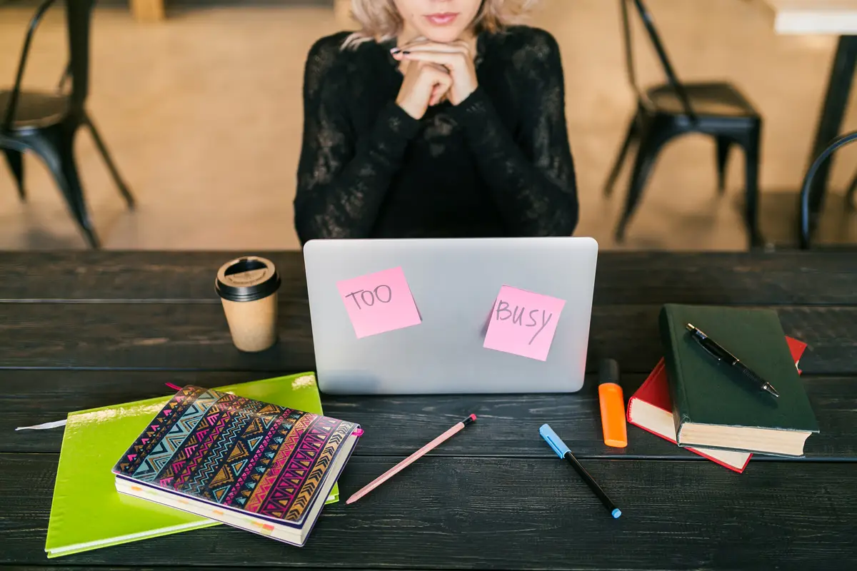Young pretty busy woman working on laptop, busy paper stickers, consentration, student in class room, top view on table with stationery, do not disturb