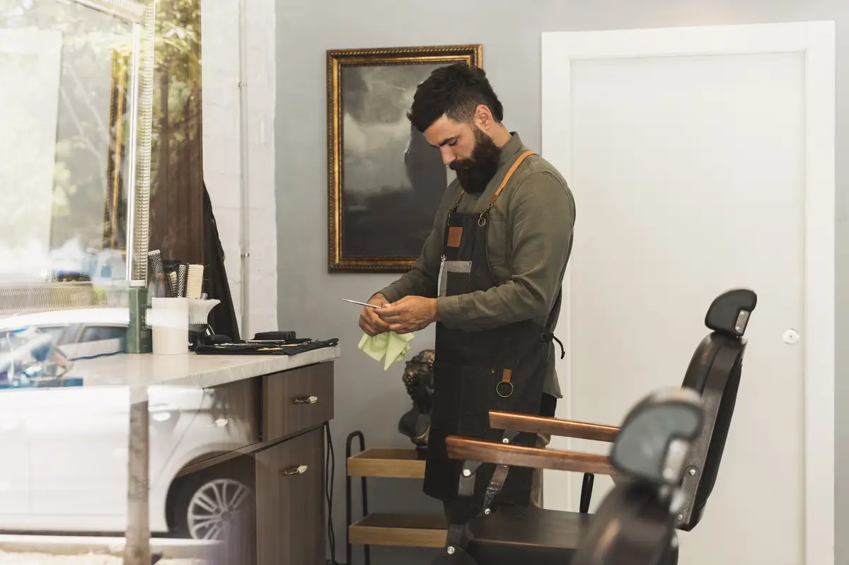 Hairdresser preparing equipment for work in barber shop