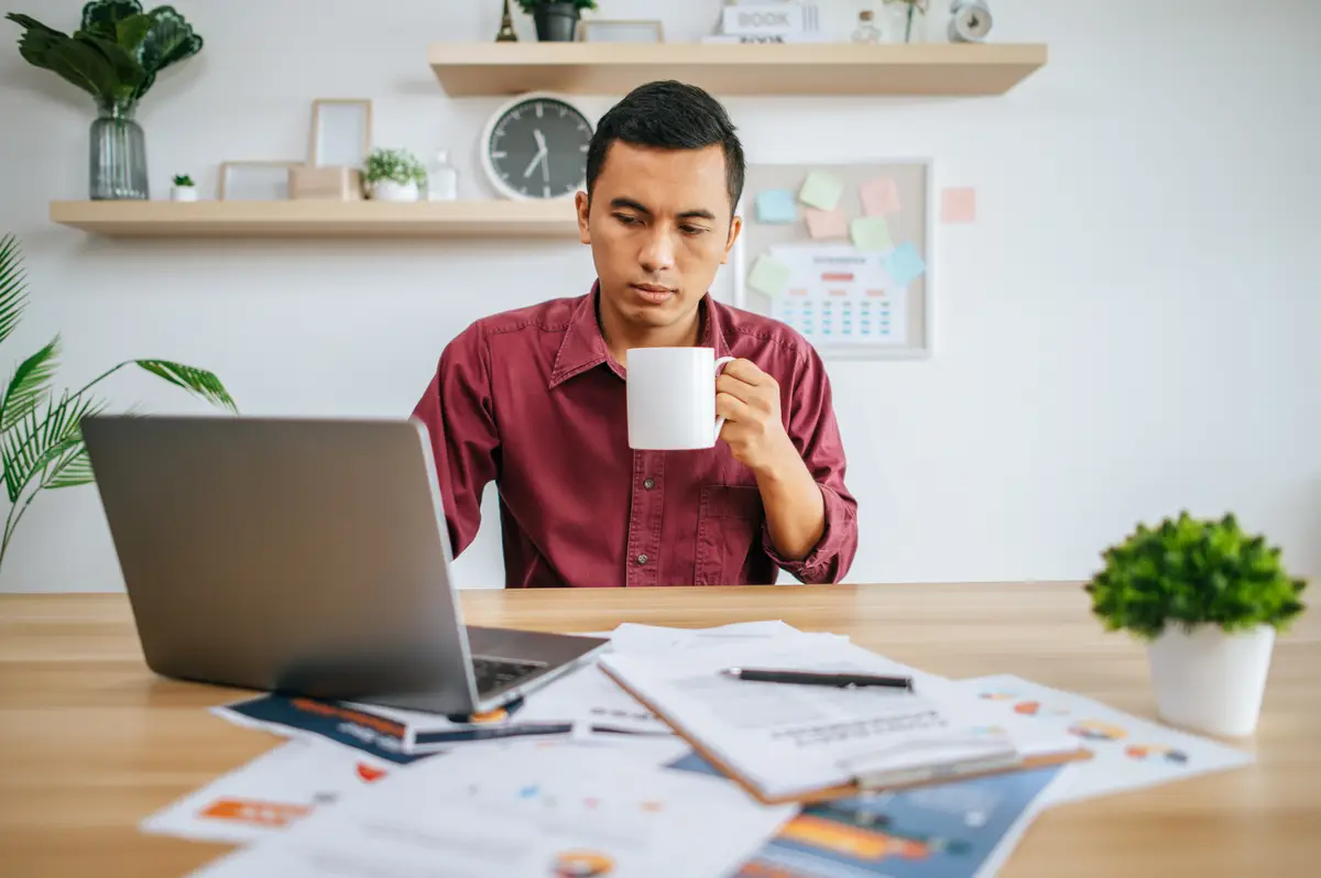 Man working with laptop and holding coffee cup